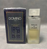 Front view of Domino Paris Eau De Toilette spray sealed box and Perles De Lalique used frosted bottle with cap.
