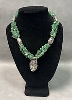 Front view of vintage necklace displaying green semi-precious stone chips, ornate silver beads, and central 925 marked silver pendant with decorative engravings.