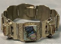 Front view of the vintage sterling silver Mexican alpaca bracelet showing abalone shell insets and carved silver details.