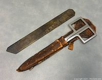Vintage 9-inch scissors with square metal handles resting in worn brown leather case alongside a metal ruler with geometric shapes.