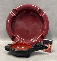 Red ceramic ashtray, black bird-shaped ashtray, and vintage lighter grouped for scale and detail