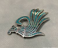 Front view of Native American sterling silver turquoise inlay bird brooch showing bird with detailed feather design and turquoise stone inlays in silver setting.