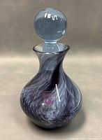 Front view of the vintage handmade glass art bottle showing blue and white swirl pattern with original Caithness label.