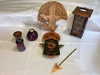 Overview of all items including wall clock, carved bird decor, lantern, ceramic vases, and candle holder placed on white surface