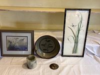 Four items displayed: two framed prints, one ceramic bowl signed Delong, and a polished shell fossil on white cloth.
