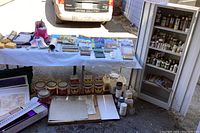 Overall photo showing large assortment of paints, brushes, stencils and supplies on table with metal storage cabinet open and filled with paint bottles.