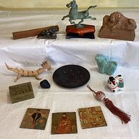Overview of eclectic decorative items including carved box, metal horse statue, cast lions, wooden dragon figure, ceramic pieces, and painted tiles.