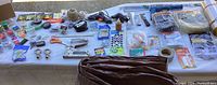 Wide view of all items on the table including measuring tools, fasteners, tapes, hooks, chains, and weather stripping.