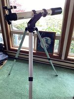 Full view of the Meade telescope on its tripod with the framed Earth picture placed behind it near the window.