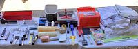 Overview of all painting tools laid out on a white cloth, showing rollers, brushes, trays, tape and drop cloths.