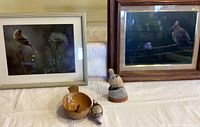 Framed bird prints with bird figurines and wooden bowl arranged on a table