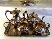 Photo of the silver-plated tea service including teapot, coffee pot, creamer, sugar bowl on an ornate silver tray.