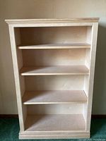 Front view of light wood bookshelf showing four shelves and open front.