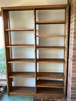 Full view of the tall wooden bookshelf showing multiple adjustable shelves and stained oak finish