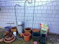 Photo showing assorted planter pots, metal garden stakes, candle lantern, and fountain with lighted sphere.