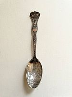 Full view of the antique sterling silver souvenir spoon showing the entire handle and bowl with the battleship engraving.