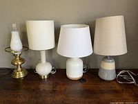 Four table lamps shown together on a flat surface, various designs and shades visible.