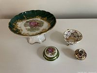 Top view of all four pieces: Limoges candy dish, Limoges small container with lid, Dresden tea cup, Royal Crown Derby tiny vase