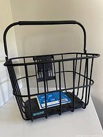 Front angled view of the black metal wire bike basket with padded handle and blue 'around' brand label on cushioned base.