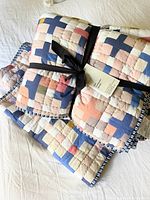 Rolled quilt and shams tied with a black ribbon showing front patchwork design