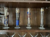 Four Ritzenhoff beer steins displayed on wood shelf showing full height and designs.