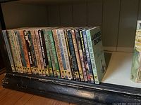 Front view of 26 vintage Ian Fleming James Bond paperback novels lined up, showing various titles and wear.