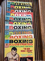 Stack of Boxing Illustrated magazines from the 1960s with colorful covers and diverse headlines related to boxing and wrestling news.