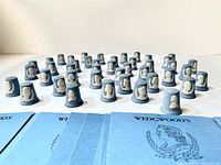 Thirty-nine blue Wedgwood Jasperware thimbles arranged in rows on white background
