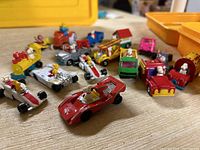 Overview of all collectible die cast cars arranged on surface showing Snoopy and Woodstock in various vehicles including race cars, trucks, and a yellow train engine.