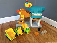 Full view of Fisher Price Lift & Load Depot toy set with vehicles, figures, and accessories arranged on the floor.