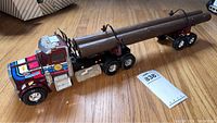 Side view of the diecast Peterbilt semi truck with a trailer carrying a large log and Great Northwest Lumber Co. logo on the cab