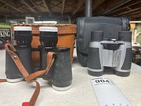 Photo showing both pairs of Kendon binoculars side-by-side with respective carry cases, on a shelf.