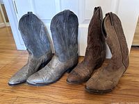 Two pairs of Laredo leather cowboy boots shown side by side, one grey pair and one brown pair, both size 11.