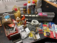 Overall view of tools, hardware, lubricants, storage drawers, cable ties, chain, and assorted fasteners spread on a table
