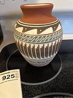 Side view of the Navajo pottery vase showing decorative patterns in white, black, and turquoise on a reddish clay body.