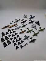 Overview of the assorted vintage model planes laid on white background showing various military aircraft with camouflage paint and other colors.