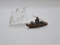 Two items displayed together: carved stone Inuit sealhunter on kayak and clear etched glass bighorn sheep