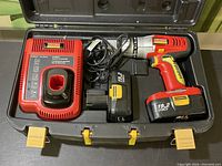 Open case showing cordless Craftsman drill, charger, spare battery, and battery attached to drill.