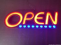 Photo of electric OPEN sign illuminated with both red letters and blue circular lights.