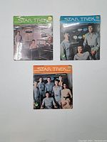 Lot of three vintage Star Trek 45 RPM records laid out on white surface showing front covers with distinctive colored top bands and cast images.