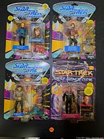 Photo showing all four Star Trek action figures in original packaging: Dr. Beverly Crusher, Commander William Riker, Romulan character, and Commander Benjamin Sisko.