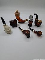 Overview of 7 assorted vintage cologne bottles in various unique pipe shapes and designs, arranged on a white background