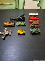 Top view of 9 vintage toy vehicles on black surface.