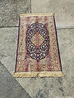 Full view of machine-made carpet showing detailed central oval floral design and fringes.