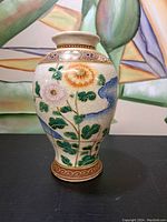 Front view of the vase showing floral design with chrysanthemums in orange, white, and purple, green leaves, and crackle glaze.