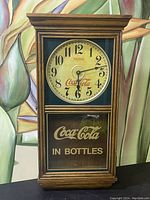 Front view of vintage Coca-Cola wall clock showing clock face with 'Drink Coca-Cola' and lower glass panel with 'Coca-Cola in Bottles' text.