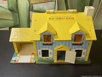 Front view of the yellow roof Fisher Price Play Family House with open door and painted flower box details.