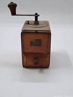 Front view showing wooden body, small drawer, and metal crank handle