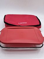 Photo showing casserole dish covered with red plastic lid placed on top of a red soft carrying case with Anchor branding.