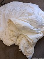 Full view of the white vintage comforter laid on the floor, showing size and texture.